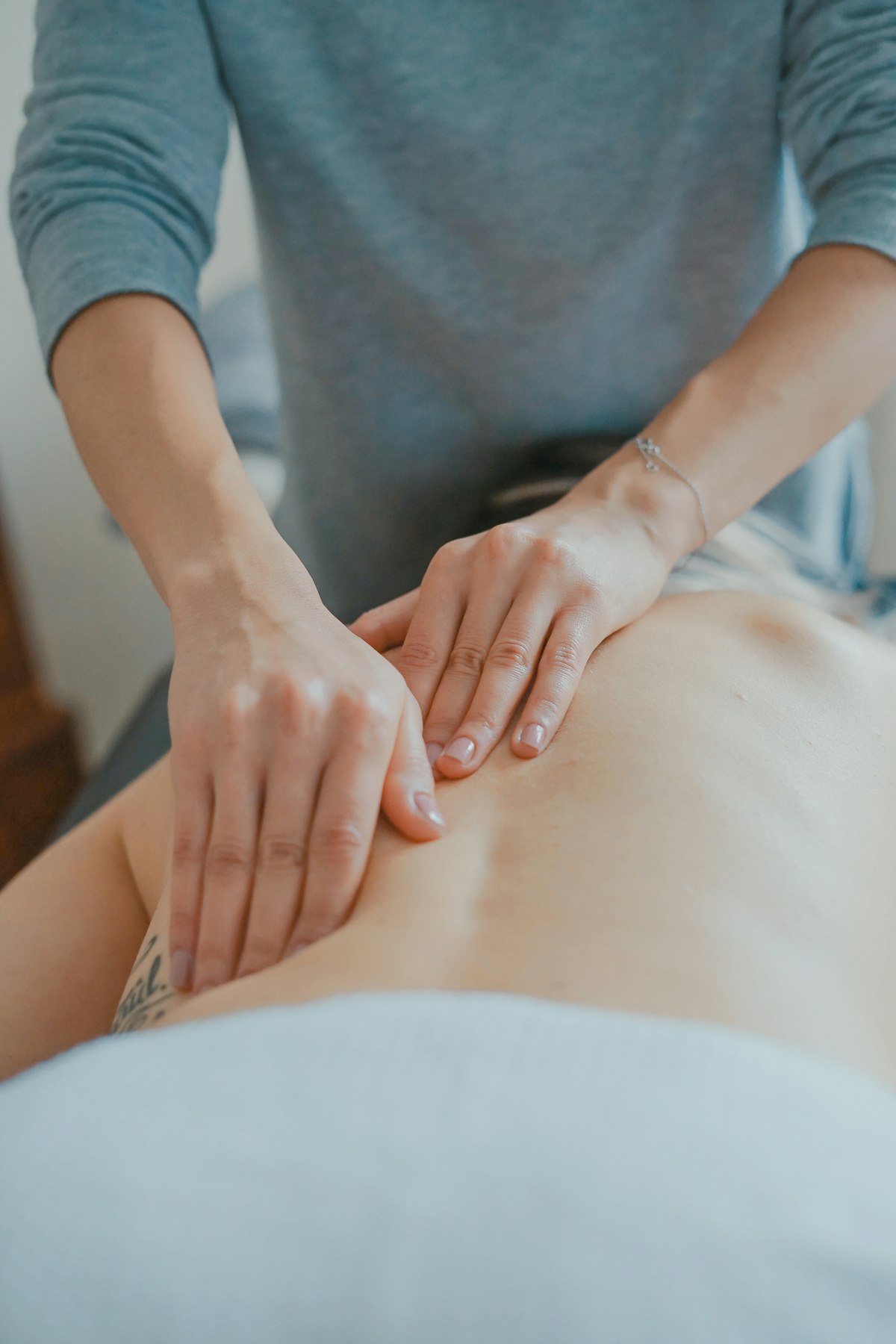 Therapist applying focused pressure along a client’s back